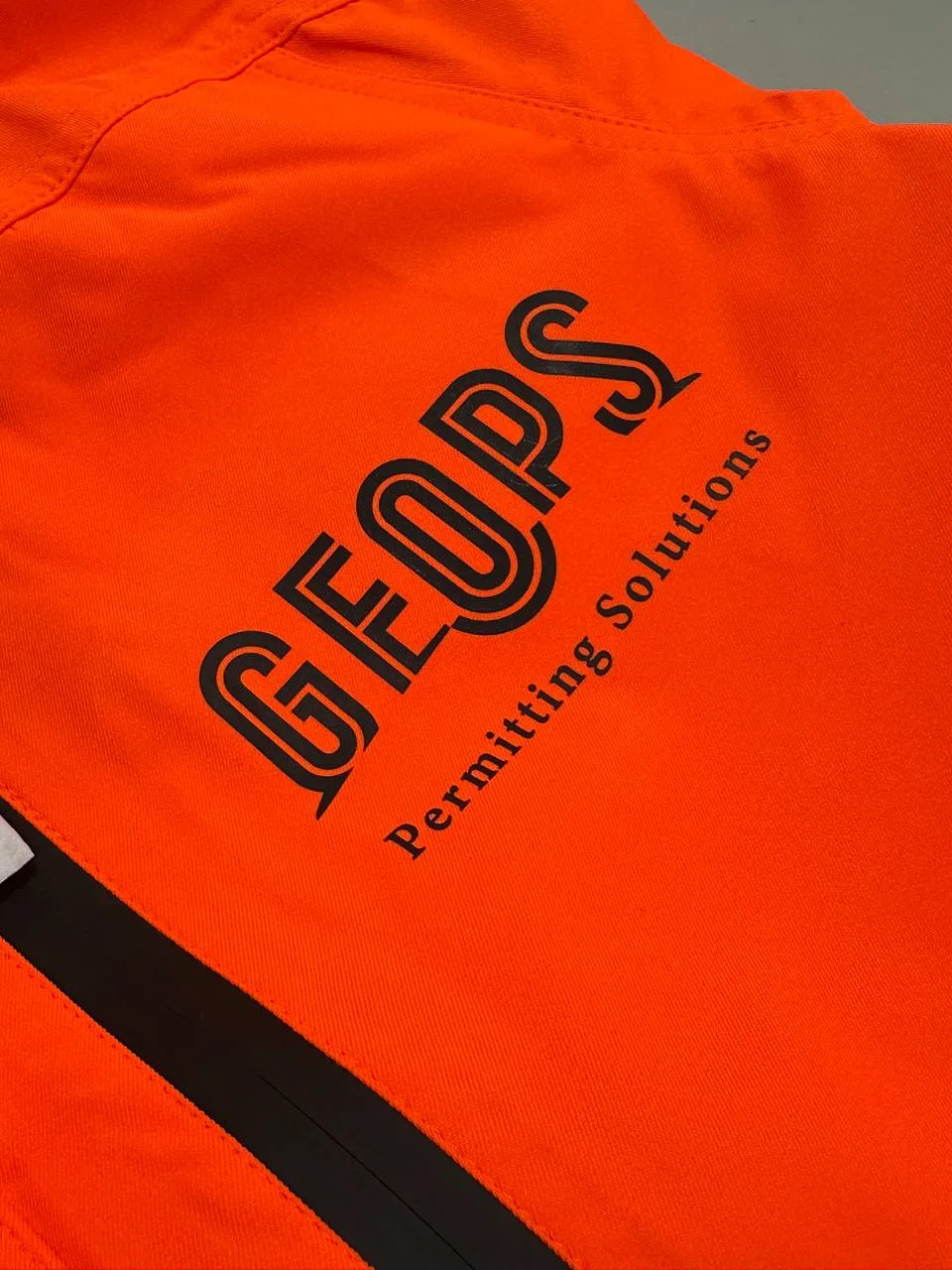 Orange Warnschutzjacke mit schwarzem Firmendruck auf der Brust