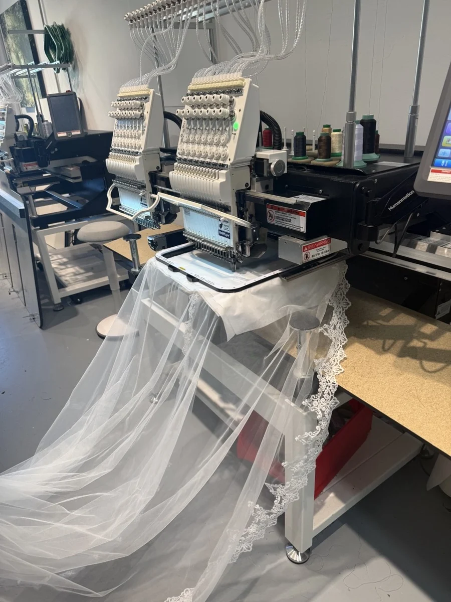 Weißer Hochzeitsschleier im Stickrahmen an einer Stickmaschine in unserer Wiener Werkstatt