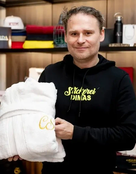 Alessandro Dimas mit einem bestickten Bademantel im Schauraum