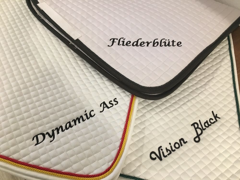 Weiße Schabracken bestickt mit Pferdenamen Fliederblüte, Dynamic Ass und Vision Black, Namensstickerei Wien