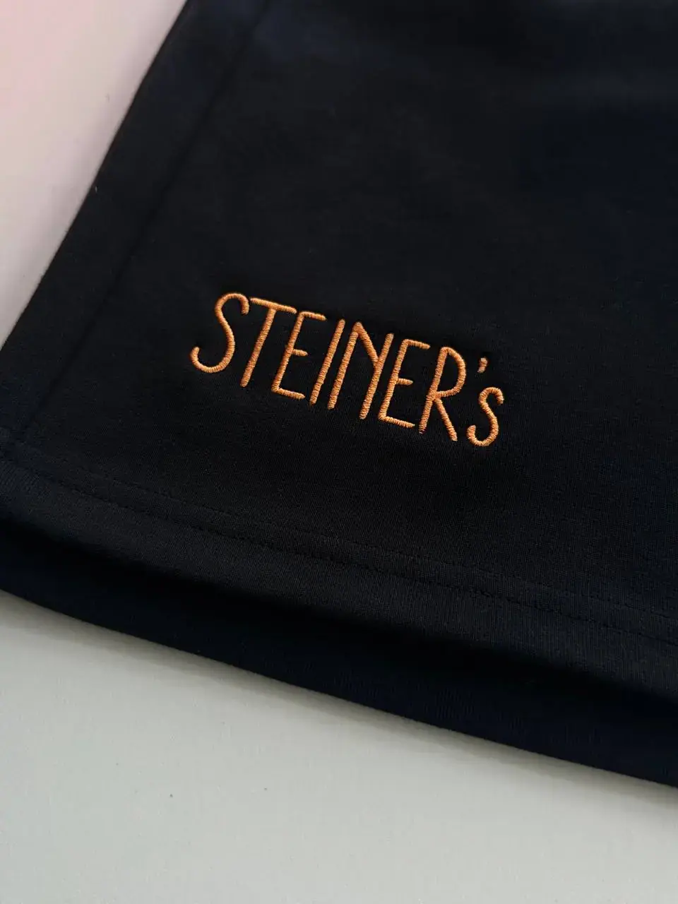 Steiners Logostickerei Gold auf schwarzem Stoff Wien
