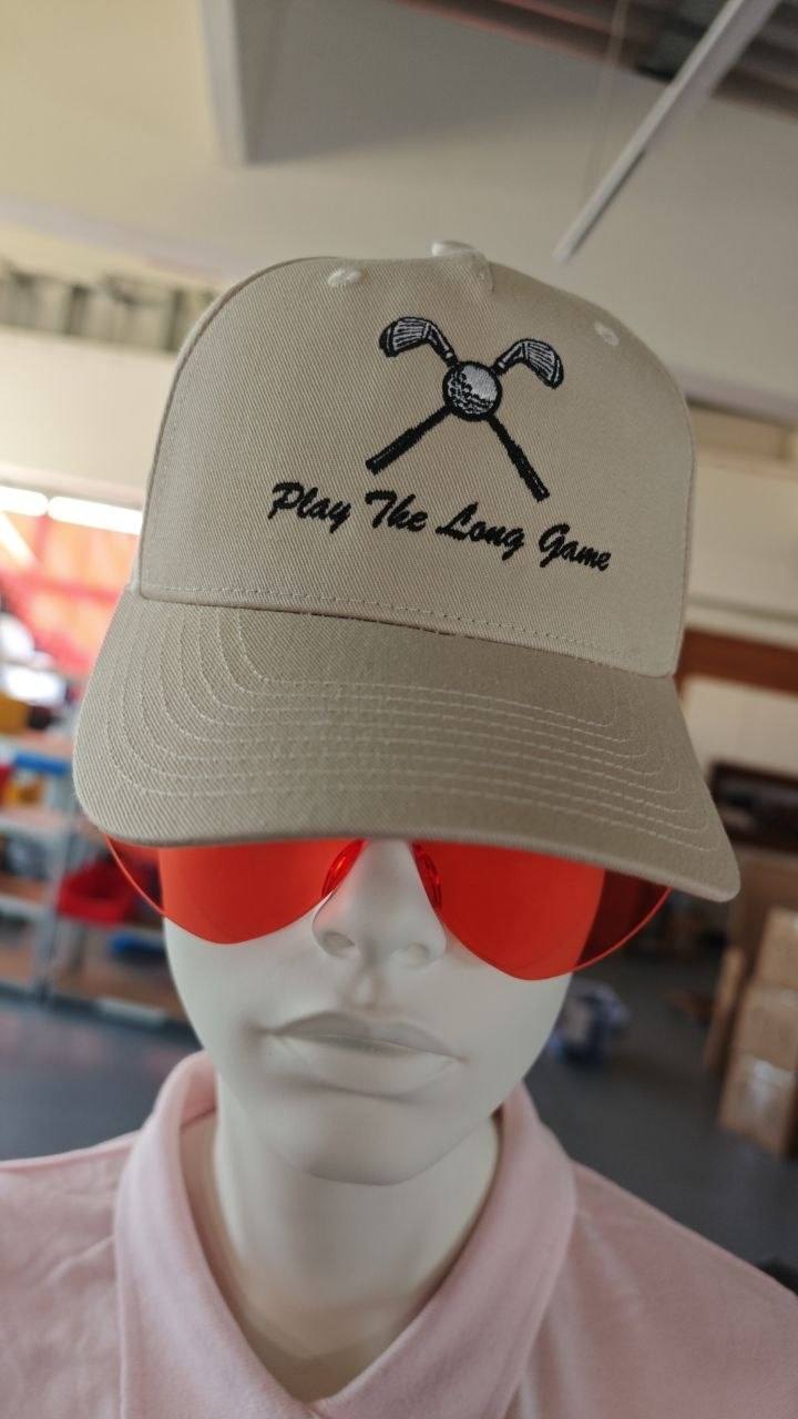 Beige Golf-Cap bestickt mit Play The Long Game Schriftzug und gekreuzten Golfschlägern, Golfsport Kappenstickerei Wien