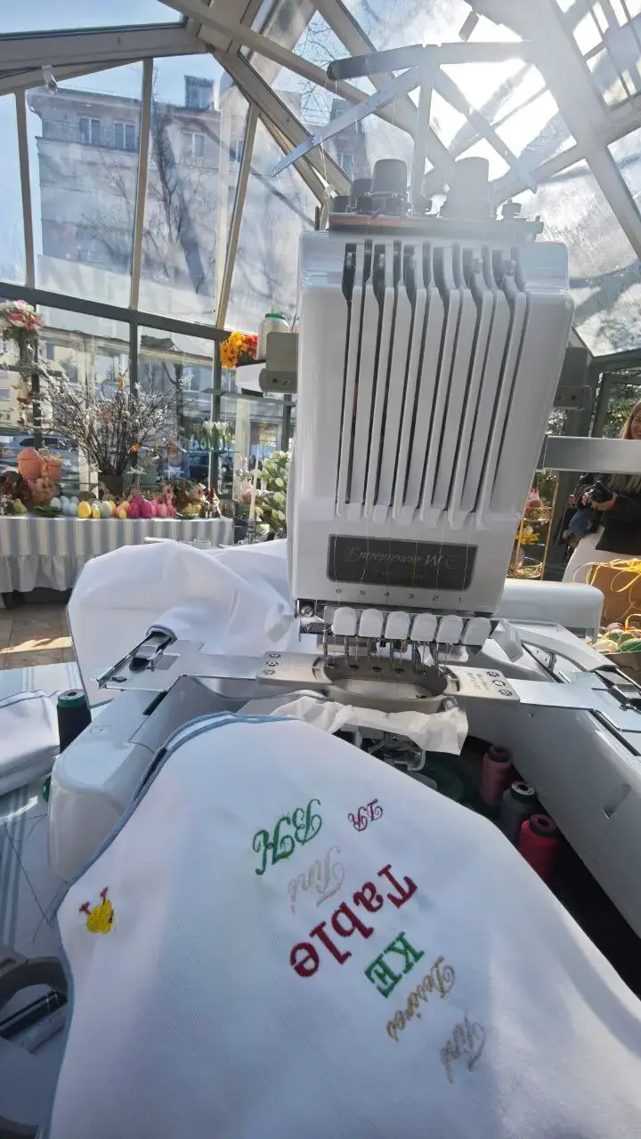 Stickmaschine mit Schriften-Demo, verschiedene Stickmuster auf weißem Stoff Wien