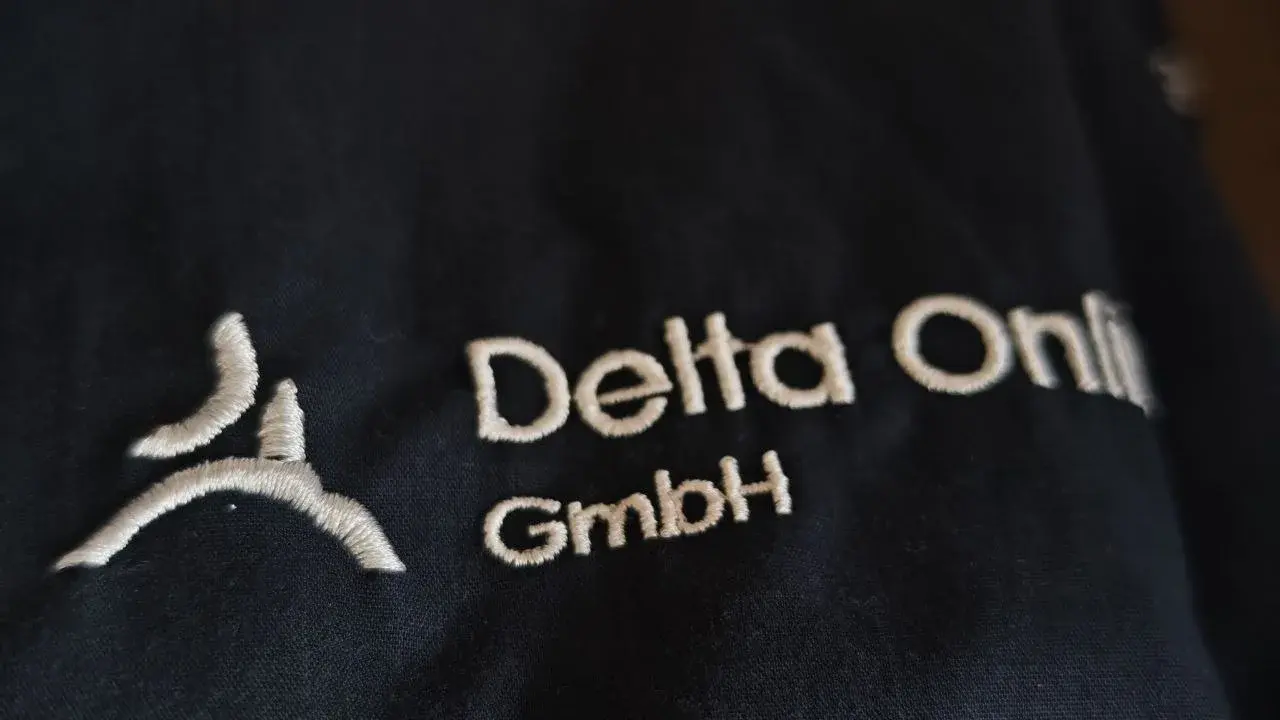 Firmenlogo in Weiß auf schwarzem Textil gestickt