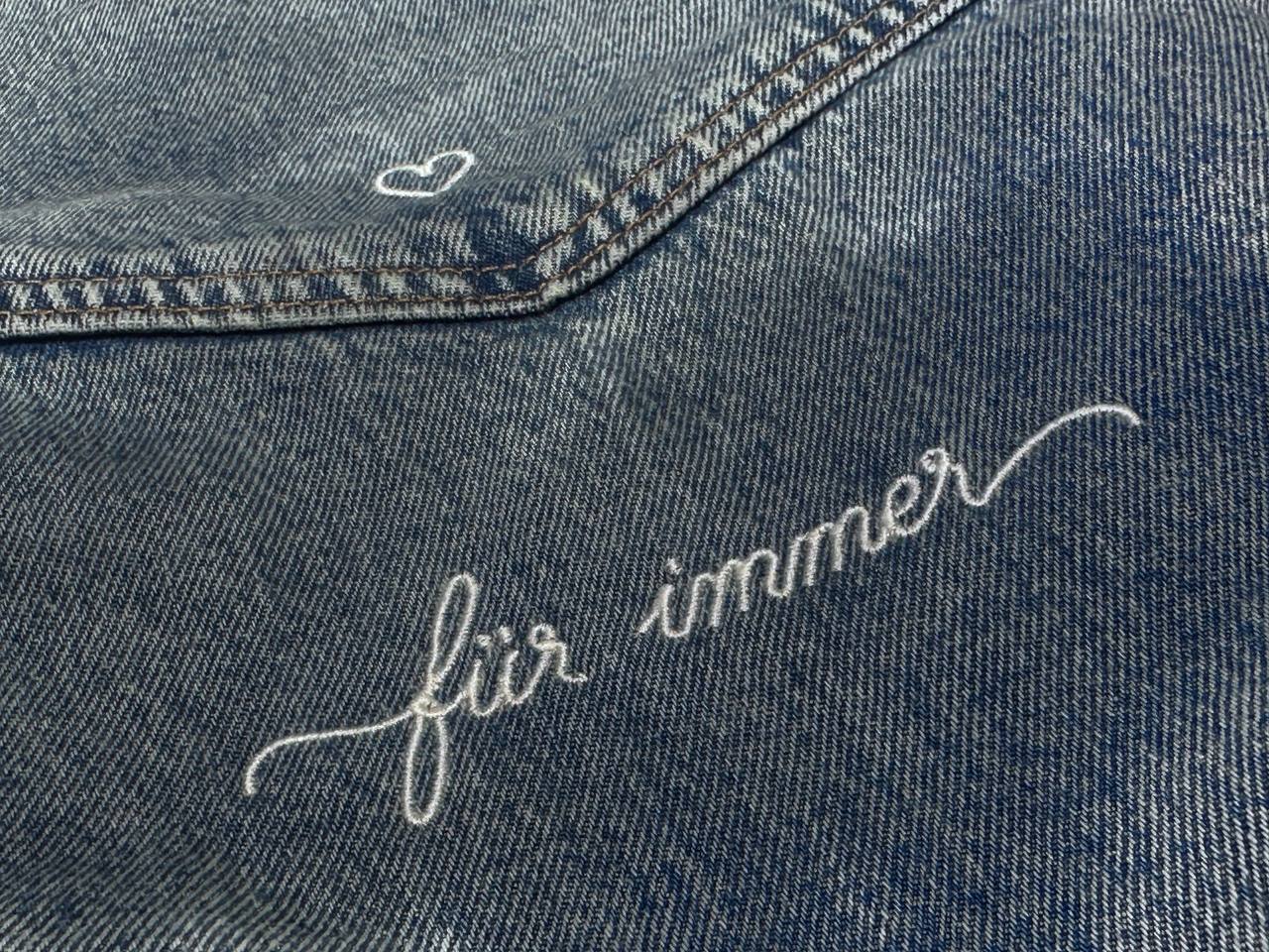 Heller Schriftzug in Schreibschrift auf Denim gestickt, Detailaufnahme