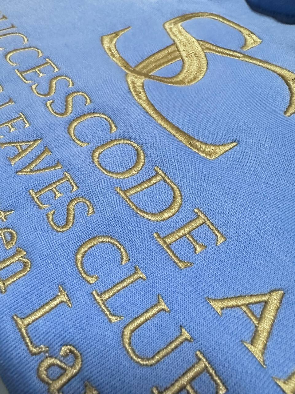 Goldene Schriftstickerei auf blauem Stoff, Detailaufnahme