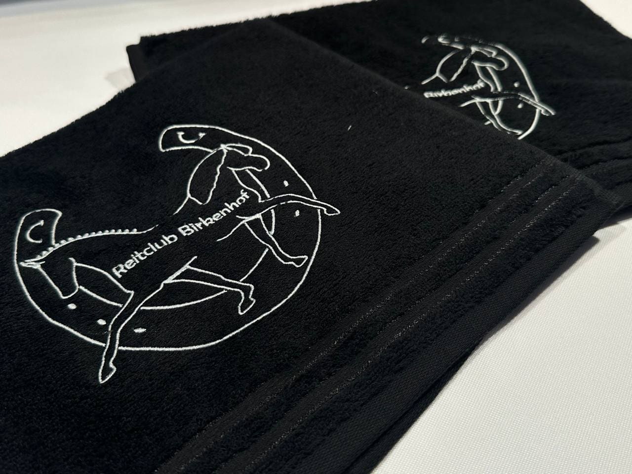 Reitclub Birkenhof Vereinslogo gestickt auf schwarzen Frottee-Handtüchern, Handtuch Stickerei Wien