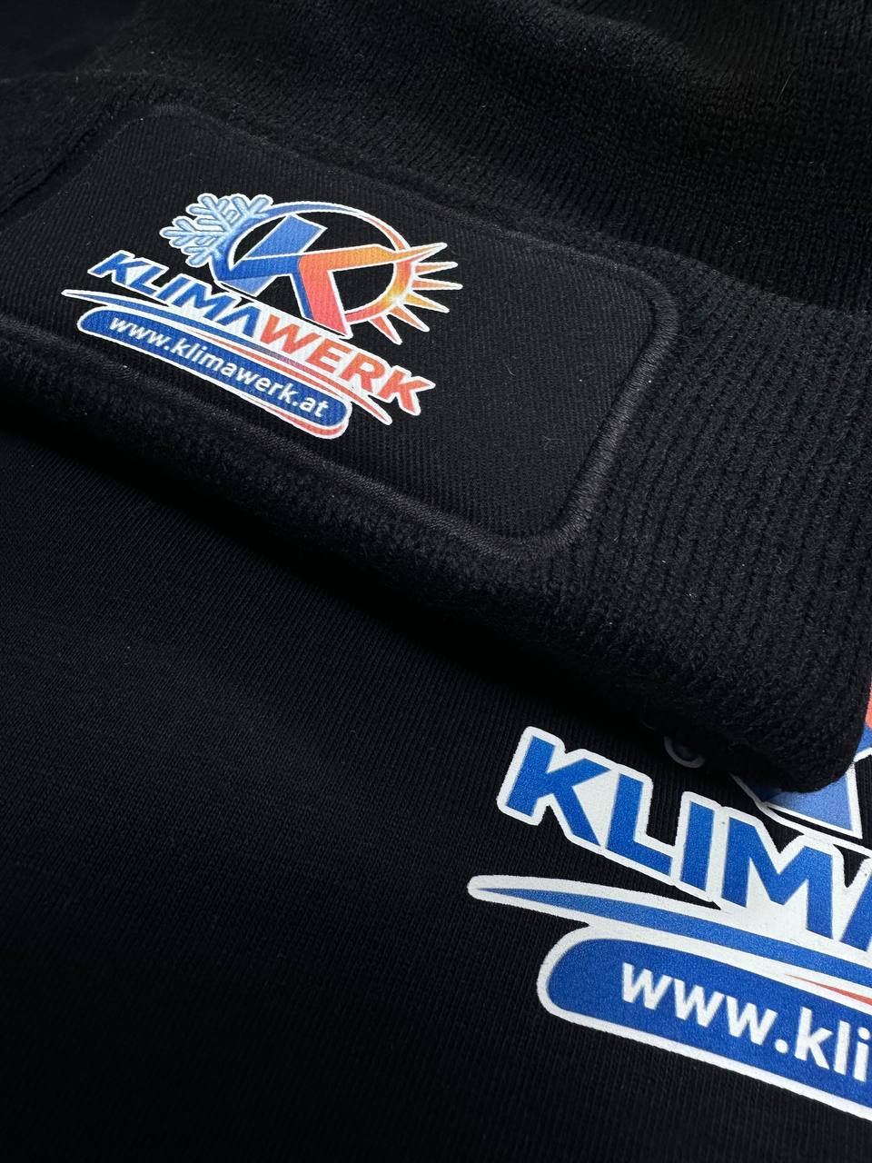 Nahaufnahme einer Logostickerei auf schwarzer Arbeitsjacke und Haube
