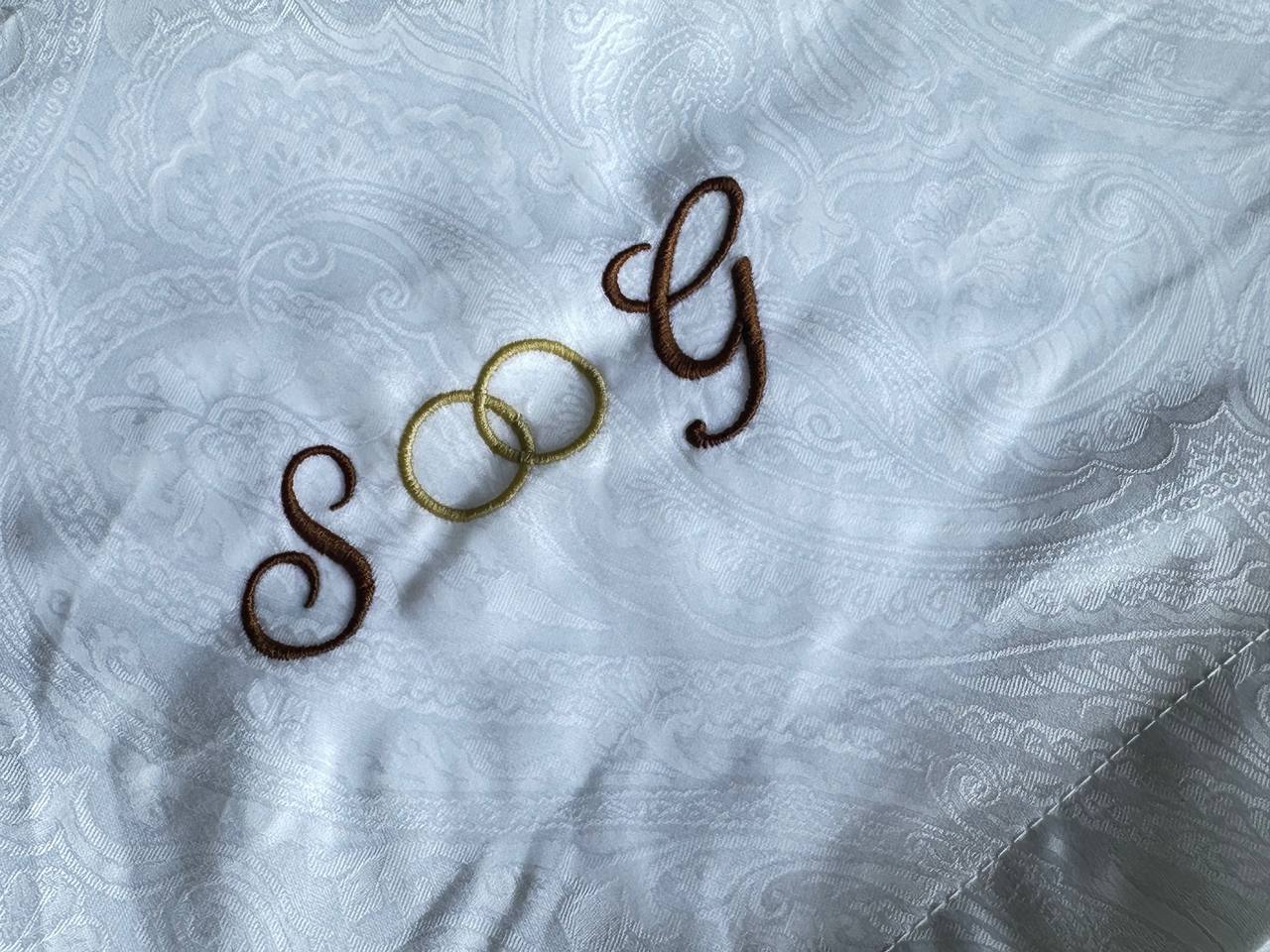 Zweifarbiges Monogramm auf weißem Textil gestickt, Detailaufnahme