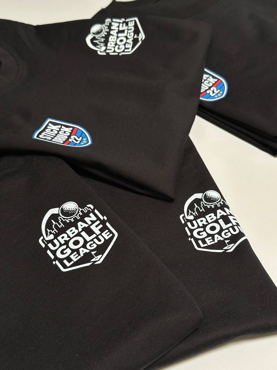Stapel von Urban Golf League Textilien mit STICKDRUCK22 Patch und Frontprint