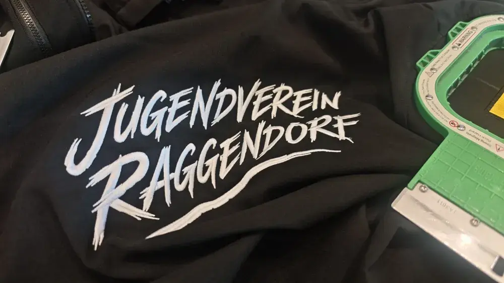 Vereinsjacke mit Logo im Stickrahmen während der Produktion