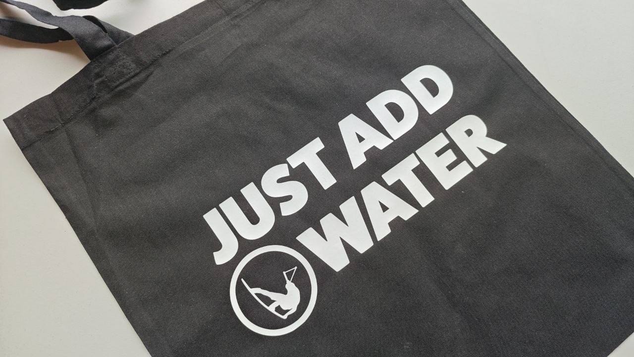 Schwarze Baumwolltasche bedruckt mit Just Add Water in Weiß, Messe-Giveaway Wien